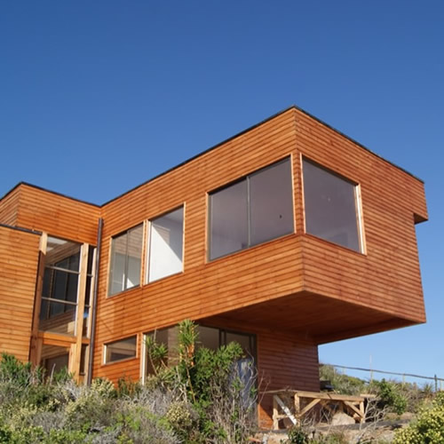 Vivienda revestida en madera con un volumen en voladizo y grandes ventanales