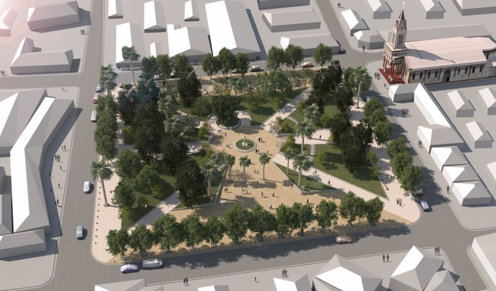 Vista aérea de una plaza con árboles, senderos y una iglesia en la esquina